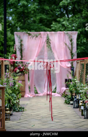 Belle cérémonie de mariage en plein air. Chaises et décorées avec une allée de mariage super bow. Arche de mariage fait de tissu et de fleurs blanches et roses sur un Banque D'Images