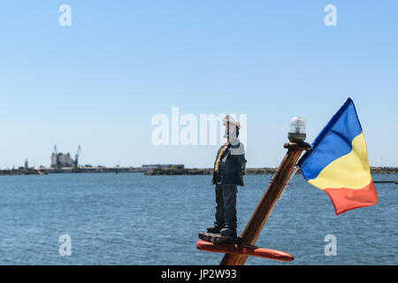 Un marin toy et le bleu, jaune et rouge du drapeau roumain monté sur un mât du navire. La mer Noire à l'arrière-plan Banque D'Images