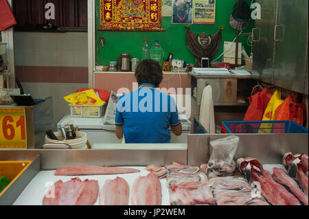 27.07.2017, Singapour, République de Singapour, en Asie - Un vendeur de poisson au marché humide Chinatown prend une pause et lit le journal pendant qu'elle mange. Banque D'Images