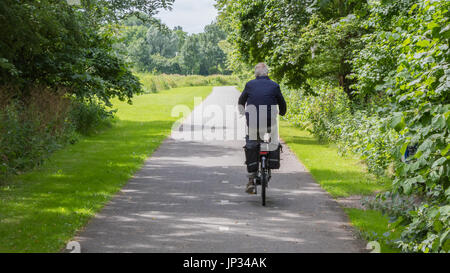 Vieil homme méconnaissable de faire du vélo sur route asphaltée. Banque D'Images