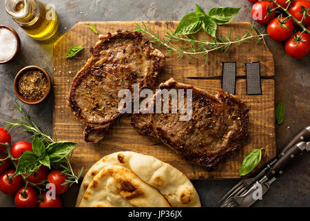 Steaks de faux-filet grillés aux herbes et épices sur une planche en bois Banque D'Images