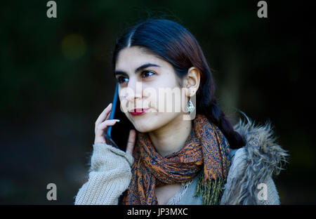 Persian girl talking on her mobile phone outdoors Banque D'Images