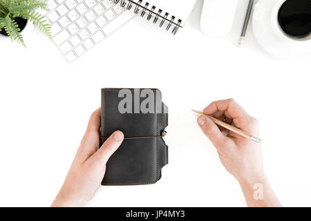 Vue de dessus de personne tenant lieu de travail au crayon et journal avec clavier de l'ordinateur, isolated on white Banque D'Images