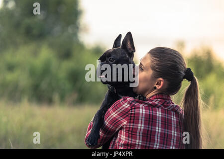 Attractive Woman kissing Bouledogue Français chiot. Banque D'Images