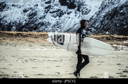 Un internaute portant une combinaison de surf et de les accompagner d'une balade sur une plage. Banque D'Images