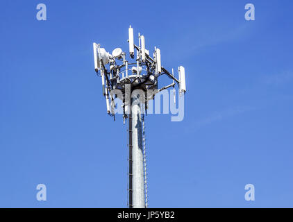 La partie supérieure du téléphone cellulaire tour de communication avec plusieurs antennes against a blue sky Banque D'Images