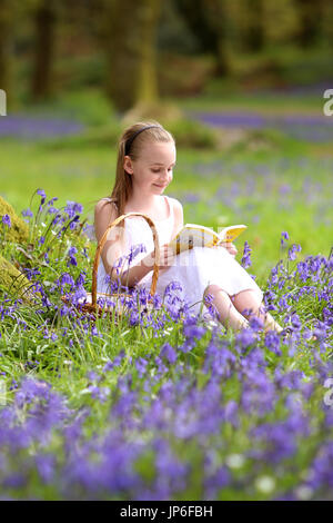 Une petite fille bénéficie d'un livre parmi les jacinthes en bois près de Honiton, Devon, UK Banque D'Images