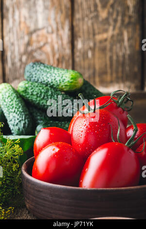 Concombres et tomates biologiques mûrs sur table en bois rustique ingrédients de cuisine, prêt à cuire. Préparation de légumes de décapage Banque D'Images