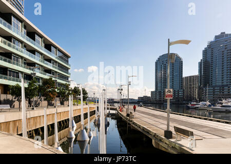 Docklands, Melbourne, Victoria, Australie. Bâtiments et au bord de l'eau, marina et du verre en mousseux soleil. Banque D'Images