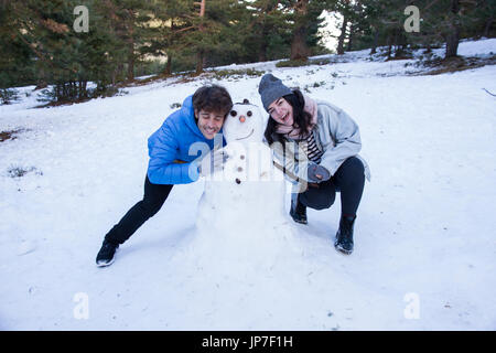 Les amateurs de profiter de la neige avec un bonhomme à nez de carotte. Ils sont heureux, pour une journée de vacances à la montagne. Banque D'Images