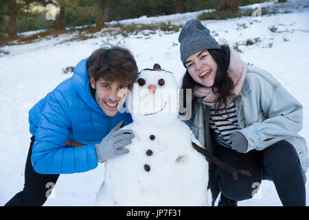 Les amateurs de profiter de la neige avec un bonhomme à nez de carotte. Ils sont heureux, pour une journée de vacances à la montagne. Banque D'Images