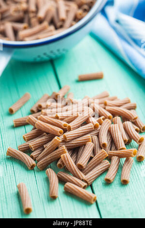 Pâtes rigatoni séché sur vert table de cuisine. Les pâtes de semoule foncé. Banque D'Images