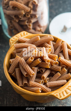 Pâtes rigatoni séchés dans un bol. Les pâtes de semoule foncé. Pâtes alimentaires non cuites. Banque D'Images