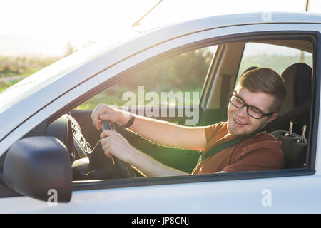 Heureux beau jeune homme brun dans un T-shirt à la conduite d'une voiture Banque D'Images