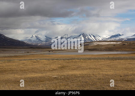 Les gens qui marchent le long des routes dans Adventfjorden avec des montagnes enneigées en arrière-plan. Prise en Juin, Longyearbyen, Spitsbergen, Svalbard, Norvège Banque D'Images