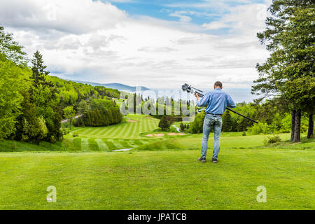 Vue paysage vert de golf avec des collines en été à La Malbaie, Québec, Canada dans la région de Charlevoix avec la photographe et trépied Banque D'Images