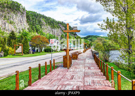 Petit-Saguenay, Canada - 2 juin 2017 : promenade en bois terrasse trottoir peint en rouge par rivière dans village du Québec Banque D'Images