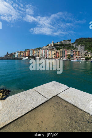 Vue depuis la jetée de bleu de la mer qui entoure l'maisons colorées typiques de Portovenere La Spezia province Ligurie Italie Europe Banque D'Images