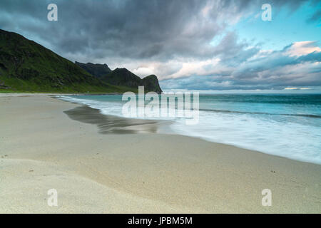 Nuages rose de minuit Soleil reflété sur le bleu de la mer et de la plage de sable fin Vestvagøy Unstad Lofoten, Norvège Europe Banque D'Images