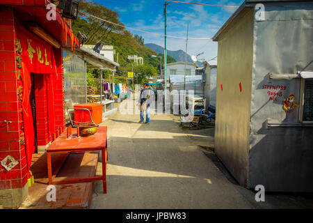 HONG KONG, CHINE - le 26 janvier 2017 : des personnes non identifiées, marcher dans un trottoir près des bâtiments métalliques utilisés comme accueil dans le vieux village de pêcheurs de Tai O avec maisons rustiques à Hong Kong Banque D'Images