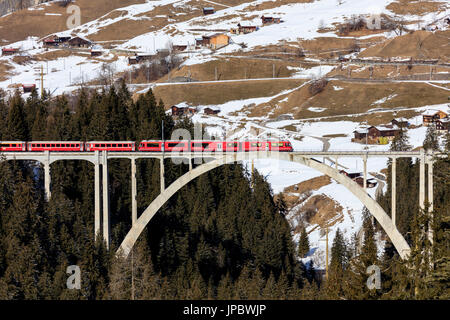 Train rouge du chemin de fer rhétique sur Langwies Viaduc entouré de bois Canton des Grisons Suisse Europe Banque D'Images