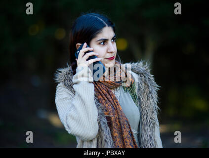 Persian girl talking on her mobile phone outdoors Banque D'Images