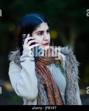 Persian girl talking on her mobile phone outdoors Banque D'Images