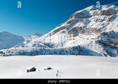 Les randonneurs en raquettes dans la vallée enneigée encadrée par des cabanes de bois à Cherz Arabba Dolomites Vénétie Italie Europe Banque D'Images