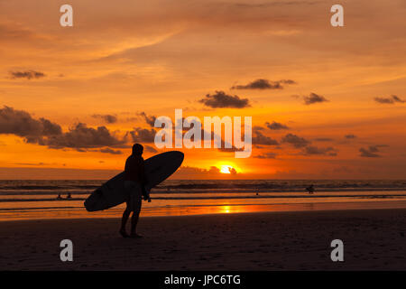 Surf Surf avec des silhouettes d'hommes dans la main on Tropical Island Beach Bali Le contexte un beau coucher de soleil colorés au-dessus de la mer Banque D'Images