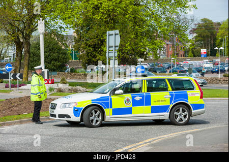 Castle Douglas, ÉCOSSE - 25 Avril 2011 : un officier de police de la circulation se trouve à côté d'une voiture de police qui est utilisé comme un barrage routier. La route était fermée Banque D'Images