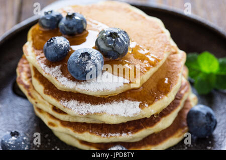 Crêpes au babeurre de bleuets dans poêle en fonte servi chaud avec du sirop d'érable sur la table en bois rustique, petit-déjeuner sain Banque D'Images