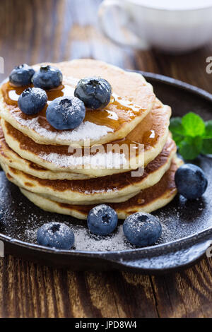 Crêpes au babeurre de bleuets dans poêle en fonte servi chaud avec du sirop d'érable sur la table en bois rustique, petit-déjeuner sain Banque D'Images