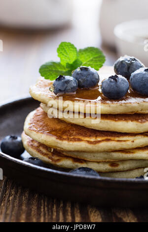 Crêpes au babeurre de bleuets dans poêle en fonte servi chaud avec du sirop d'érable sur la table en bois rustique, petit-déjeuner sain Banque D'Images