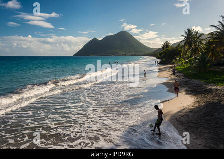 Le Diamant Beach en Martinique, avec jeune homme jouant avec une balle et femme endormie montagne en arrière-plan Banque D'Images