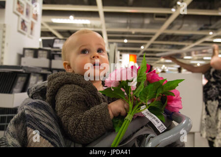 Bébé avec de fausses fleurs dans un magasin Banque D'Images