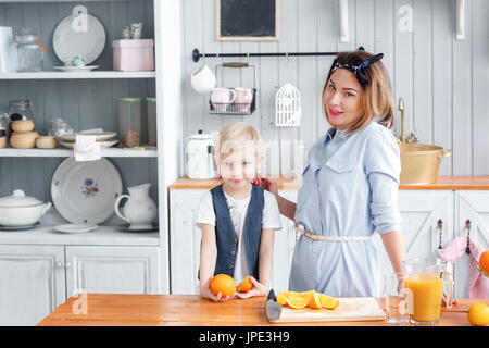 Maman coupe de fruits pour son fils. sliced oranges sur une planche à découper en bois. Petit-déjeuner sain et savoureux Banque D'Images