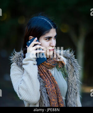 Persian girl talking on her mobile phone outdoors Banque D'Images