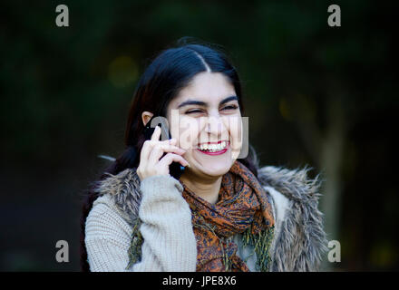 Persian girl talking on her mobile phone outdoors Banque D'Images