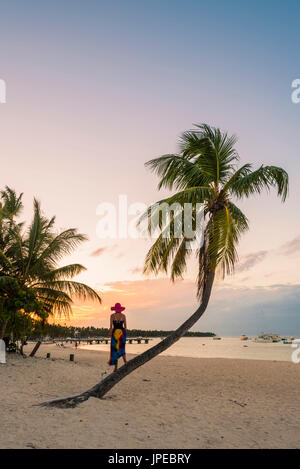 La plage de Cabeza de Toro, Punta Cana, République dominicaine. Femme debout sur le tronc d'un palmier (MR). Banque D'Images