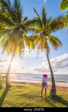 Playa Moron, Las Terrenas, Péninsule de Samana, République dominicaine. Femme se détendre sur une prairie bordée de palmiers (MR). Banque D'Images