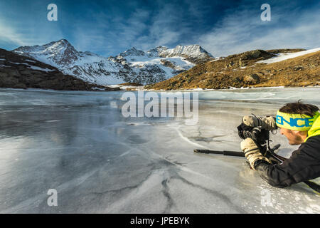 Col de la Bernina, Suisse. Un photographe en action sur un fronzen lake. Banque D'Images