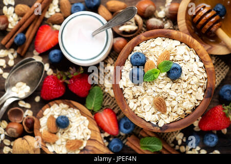 Petit-déjeuner sain concept avec l'avoine, des yaourts, des bleuets, des fraises et du miel. Vue de dessus, faible profondeur de champ Banque D'Images