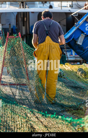 Jeune pêcheur réparant les filets de pêche, Palamos, Espagne Banque D'Images