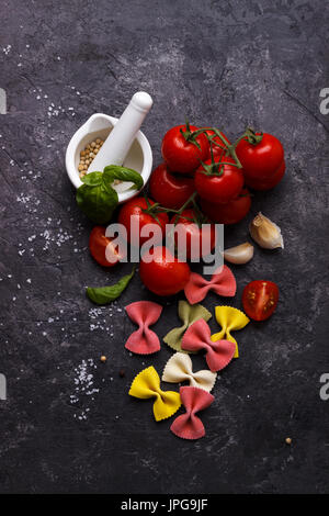 Pâtes farfalle colorés italienne, tomate et épices sur fond noir en ardoise noire Banque D'Images