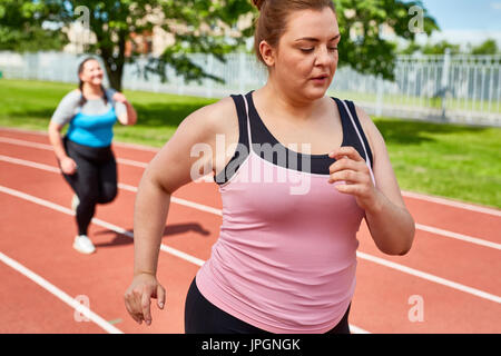 Jeune femme obèse et son ami jogging le stade moderne Banque D'Images