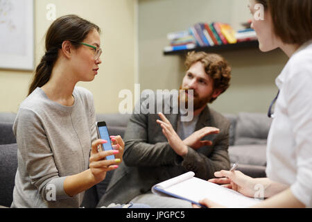 Portrait of young Asian woman accusant son mari d'adultère montrant des messages texte sur téléphone mobile dans des couples conseillant la session Banque D'Images