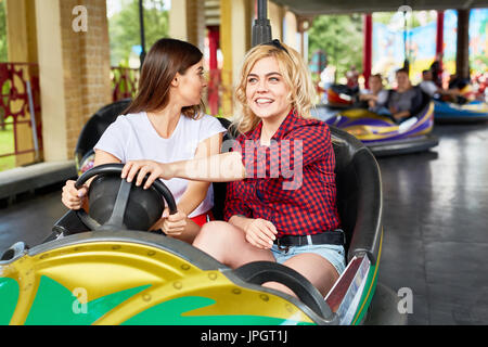 Portrait de belle jeune fille au volant voiture avec bouclier friends enjoying manèges dans park Banque D'Images