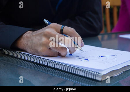 Jeune entrepreneur l'écriture d'un schéma sur une feuille vierge d'un ordinateur portable sur la terrasse. Banque D'Images