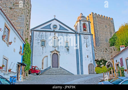 L'église St James avec l'immense tour en pierre du château médiéval de l'arrière-plan, Obidos, Portugal. Banque D'Images