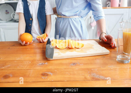 Maman coupe de fruits pour son fils. sliced oranges sur une planche à découper en bois. Petit-déjeuner sain et savoureux Banque D'Images